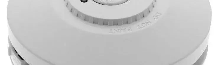 Round white smoke alarm with a smooth matte finish and a central test button feature