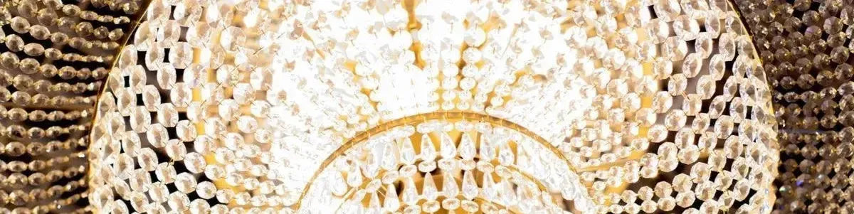 Tiered gold frame chandelier featuring cascading clear crystal beads and teardrop accents in a warm glowing light