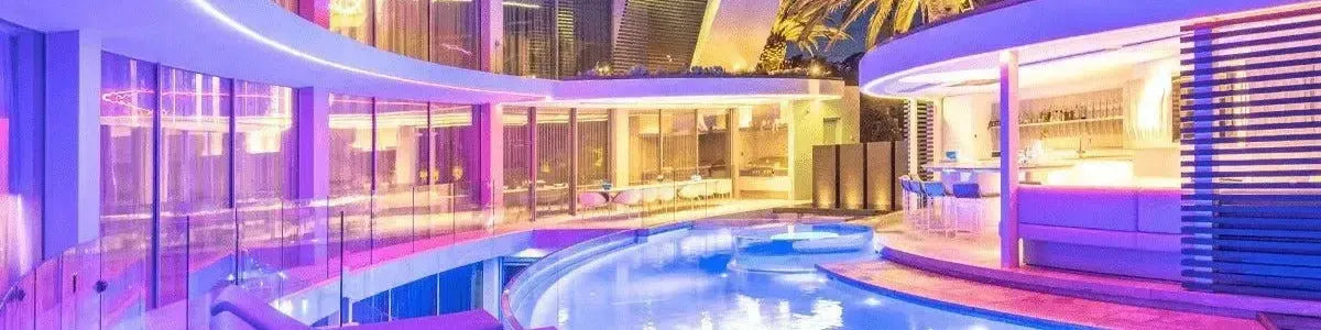 Vibrant purple LED strips illuminating the curved architectural edges of a modern luxury outdoor pool area at night