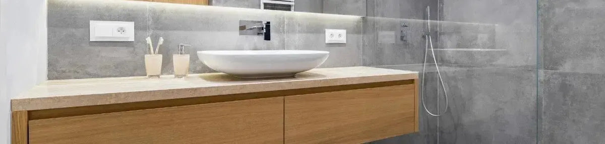 Warm timber vanity with a white vessel basin set against grey stone tiles and a glass shower screen